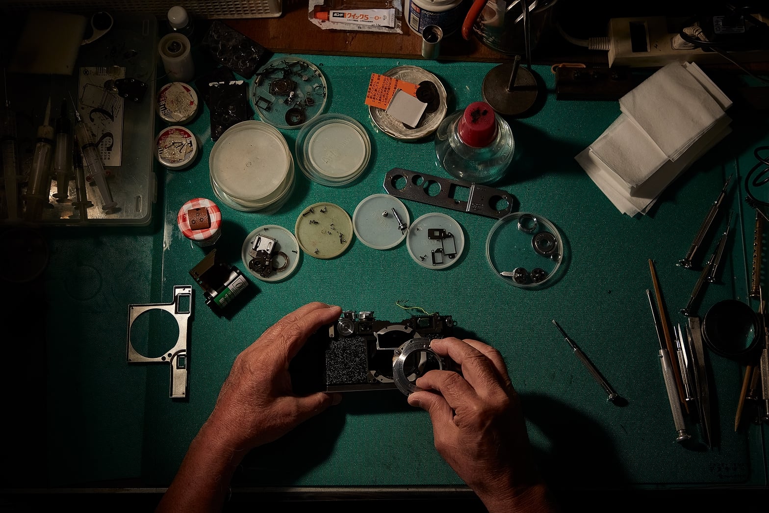 整備のために分解・清掃した後、組み戻す段階のニコンS2。作業スペースには外装部品が並んでいる。